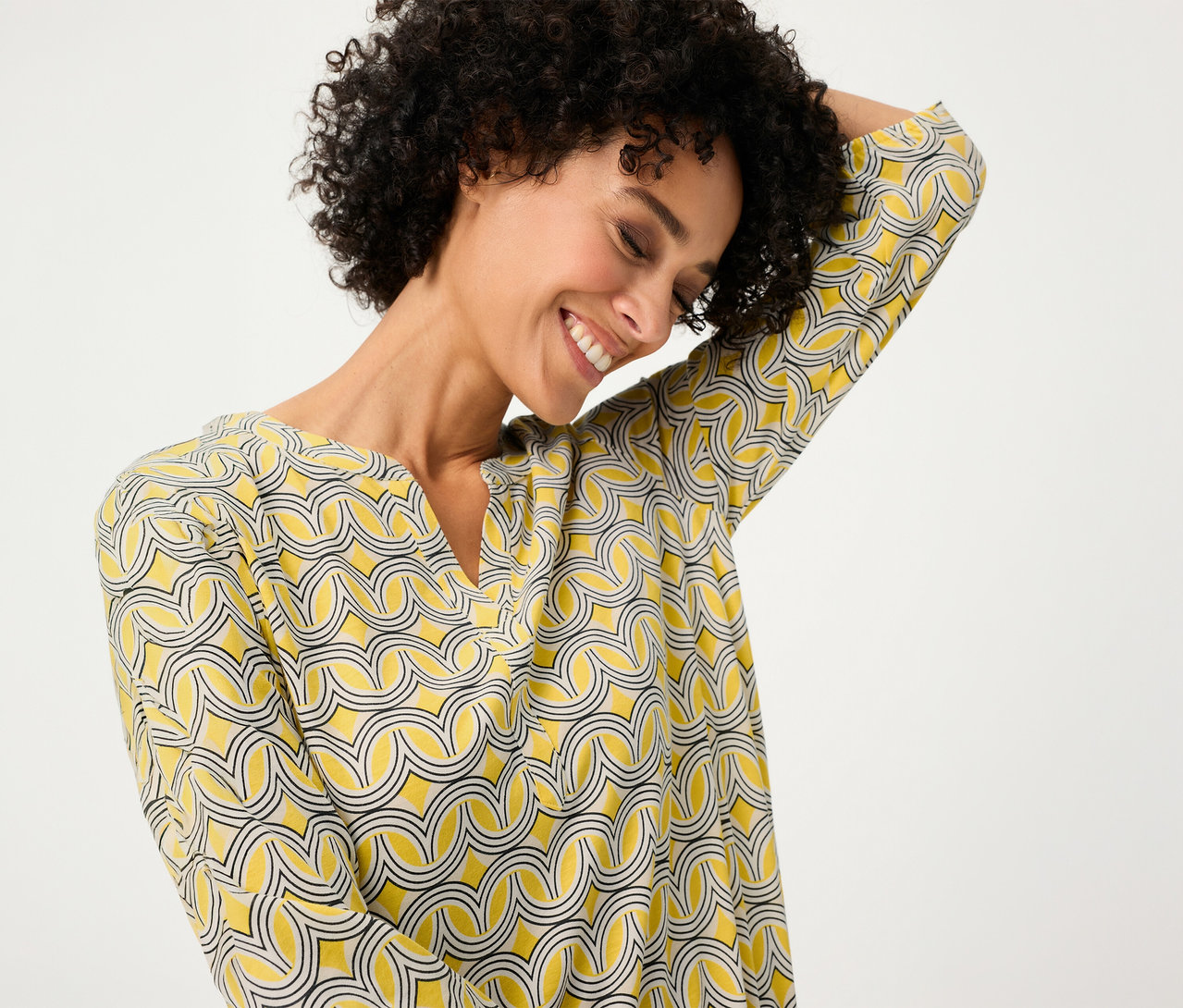 Usmievavá sa žena v žltej blúzke s 3/4 rukávmi Olsen.