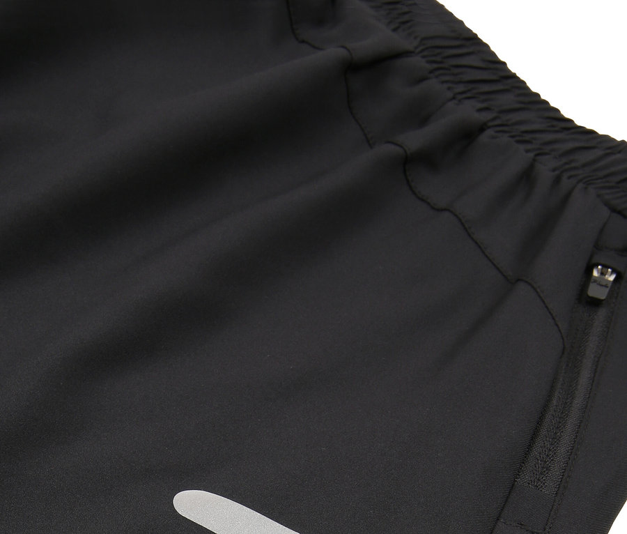 Detail čiernych šortiek s elastickým pásom, vreckom na zips a reflexnými pruhmi.