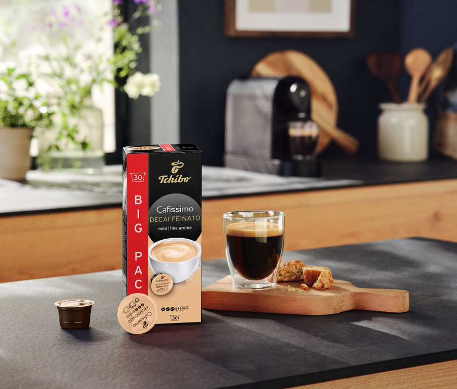Na kuchynskej linke stojí balenie kapsúl Cafissimo Decaffeinato, šálka kávy a kapsula.