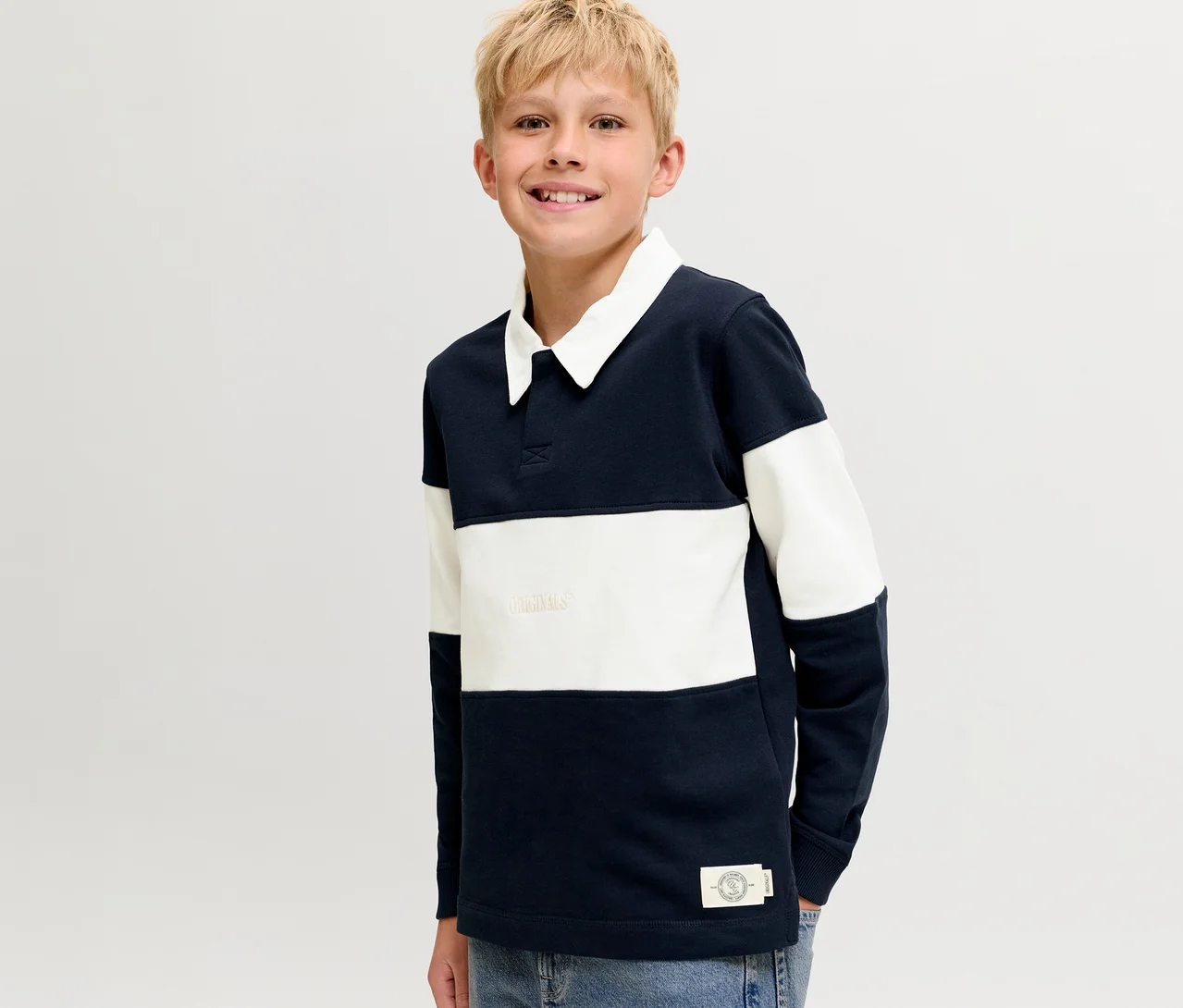 Usmiaty blonďavý chlapec v modro-bielom pruhovanom Jack&Jones Polo Sweateri s bielym golierom.