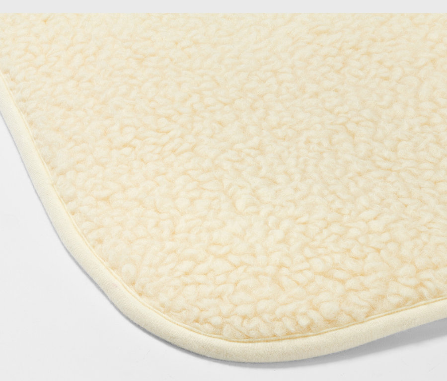 Detail rohu béžovej podložky na jogu so strižnou vlnou.