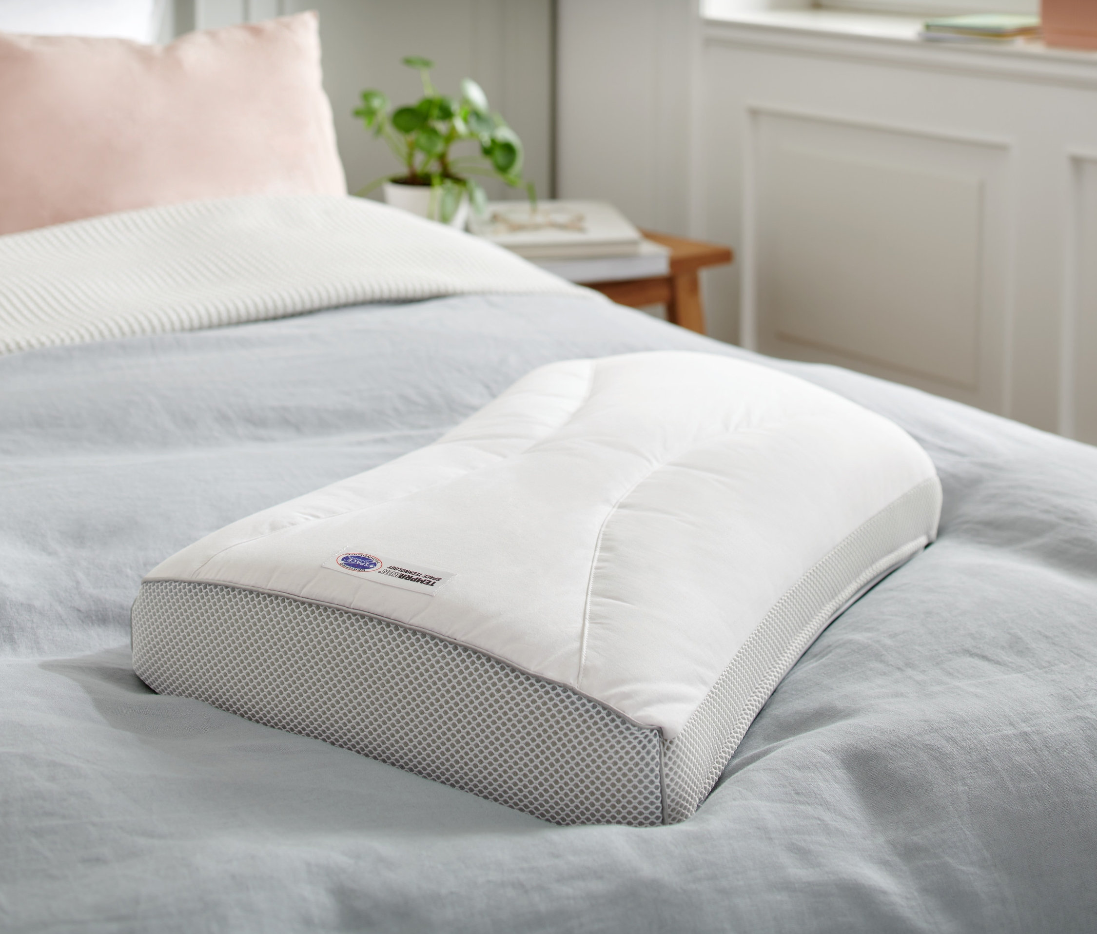 Vankúš Temprakon X-Zone leží na posteli s modrým prehozom.