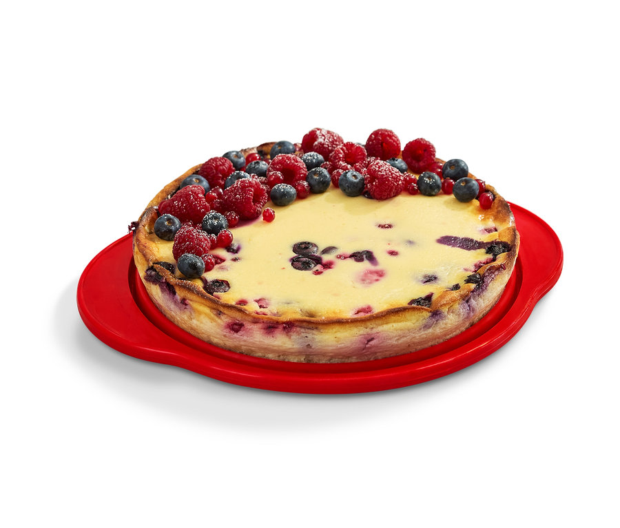 Torta zdobená ovocím na červenej skladacej forme na koláč.