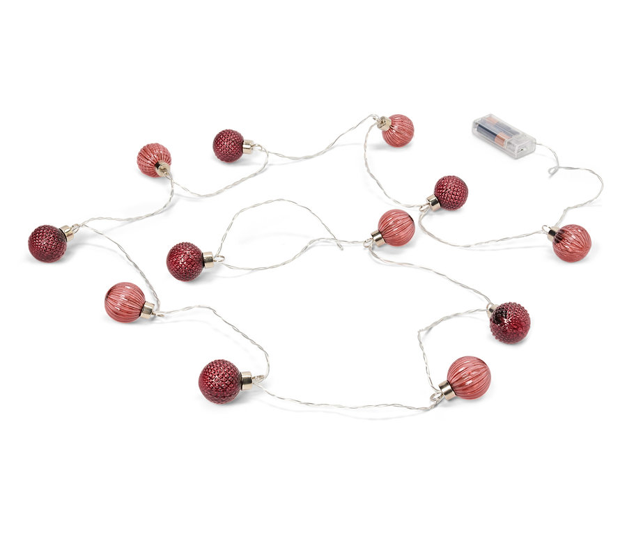 Svetelná reťaz s červenými guľami a batériami leží na bielom pozadí.