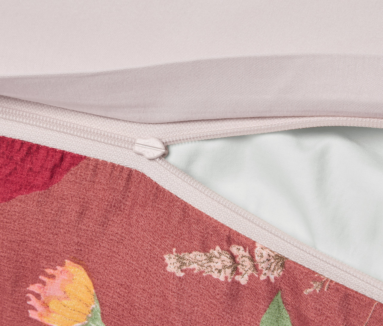 Detailný záber obliečky na vankúš s kvetinovým vzorom a zipsom.