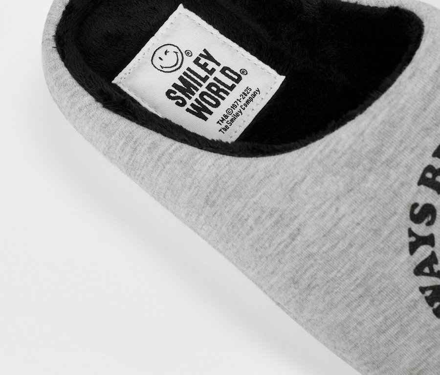 Detail sivého textilného hausschuhe SMILEYWORLD® s čiernou vnútornou podšívkou a štítkom s logom.