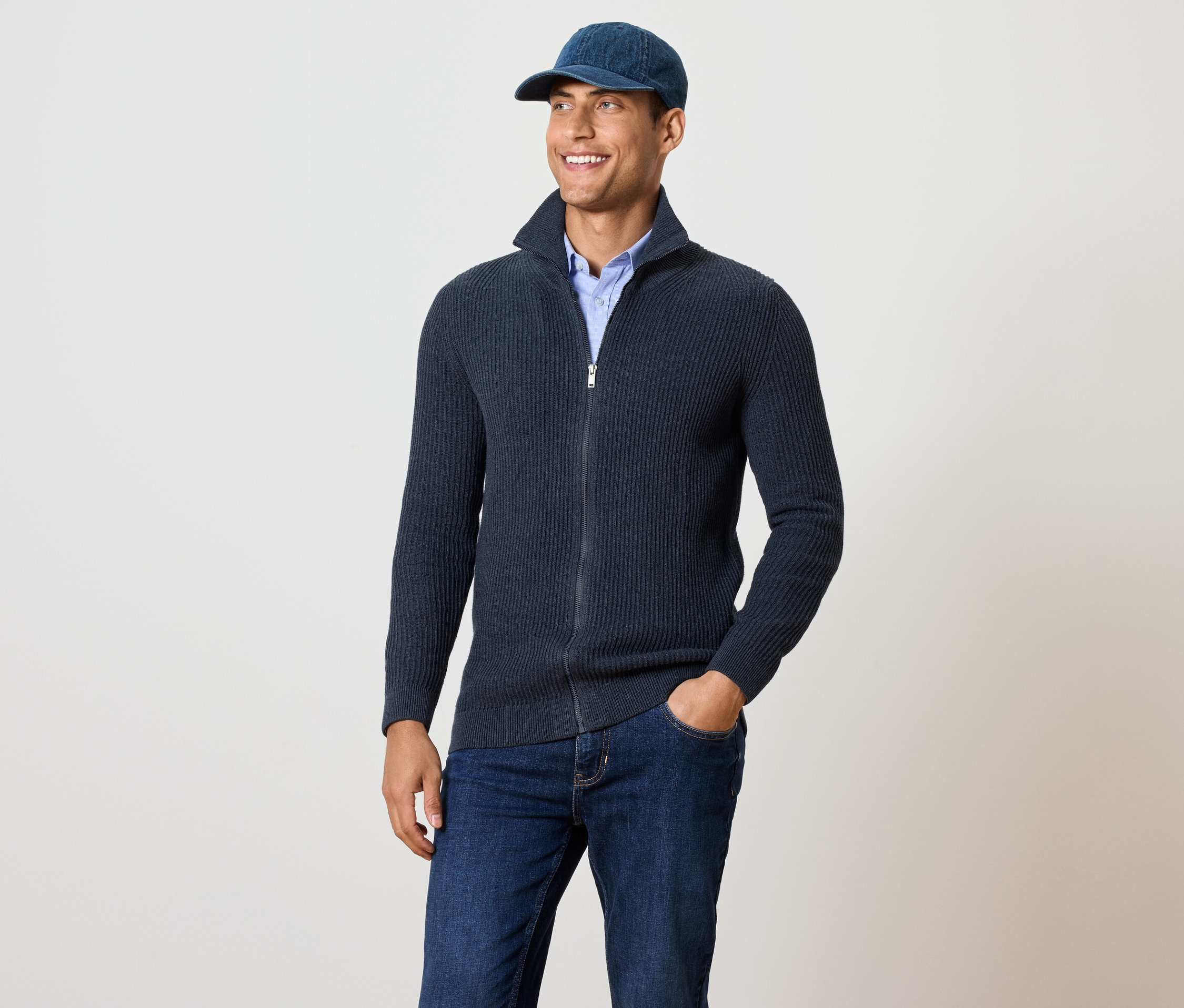 Muž má na sebe pletený sveter, námornícky modrý s melírom.