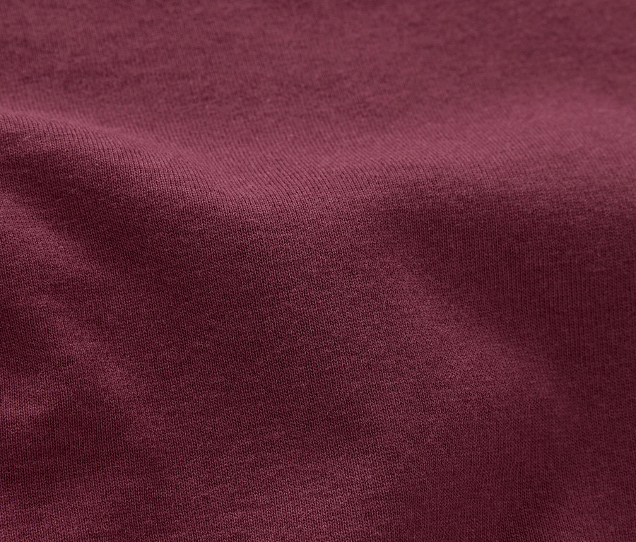 Detailný záber na textúrovanú látku bordovej farby.
