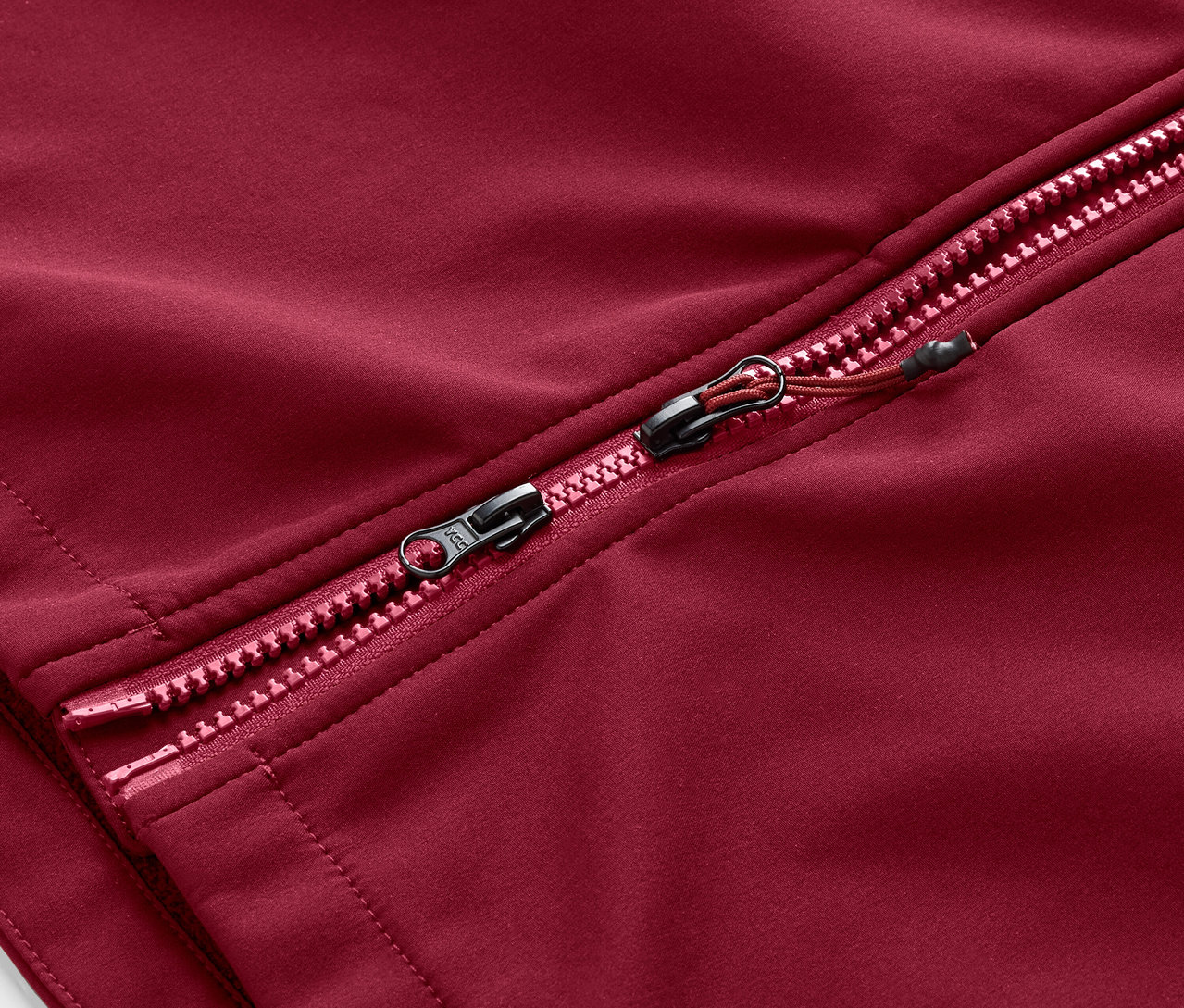 Detail zipsu tmavočerveného softshellového kabátu.