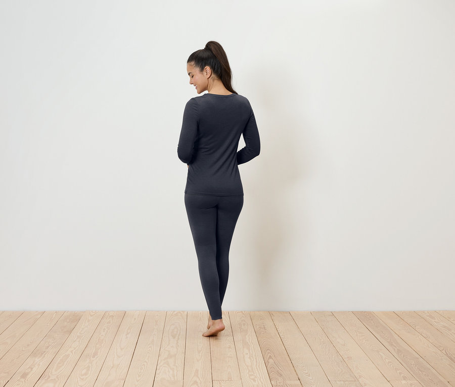 Žena stojí chrbtom k fotoaparátu a má na sebe tmavosivú termobielizeň.