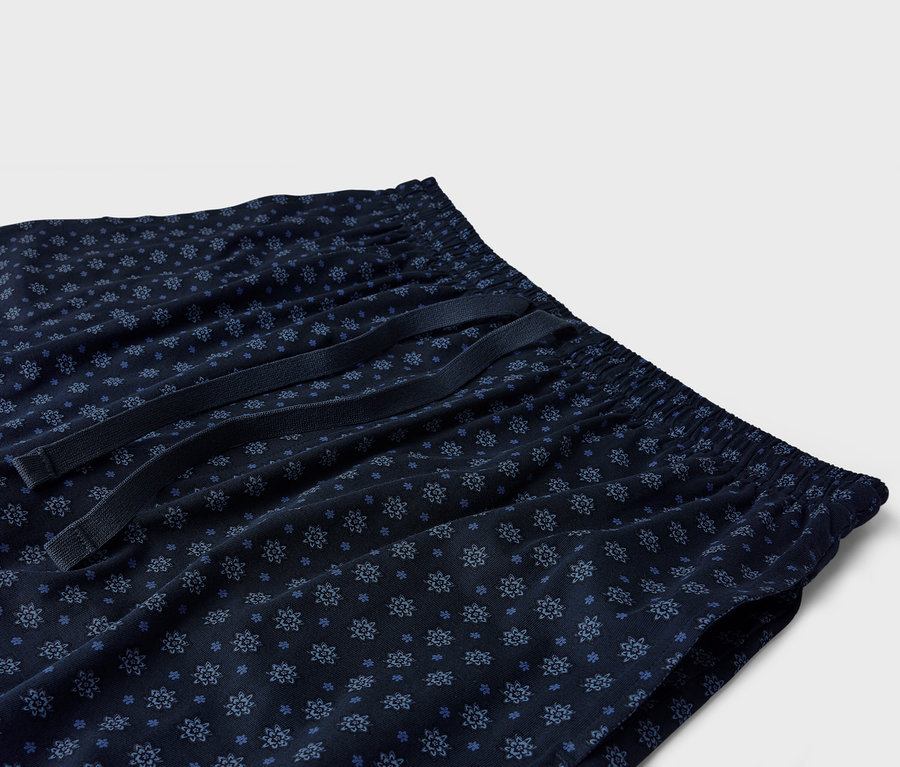 Detailný záber na tmavomodré pyžamové nohavice s modrým kvetinovým vzorom a šnúrkou.