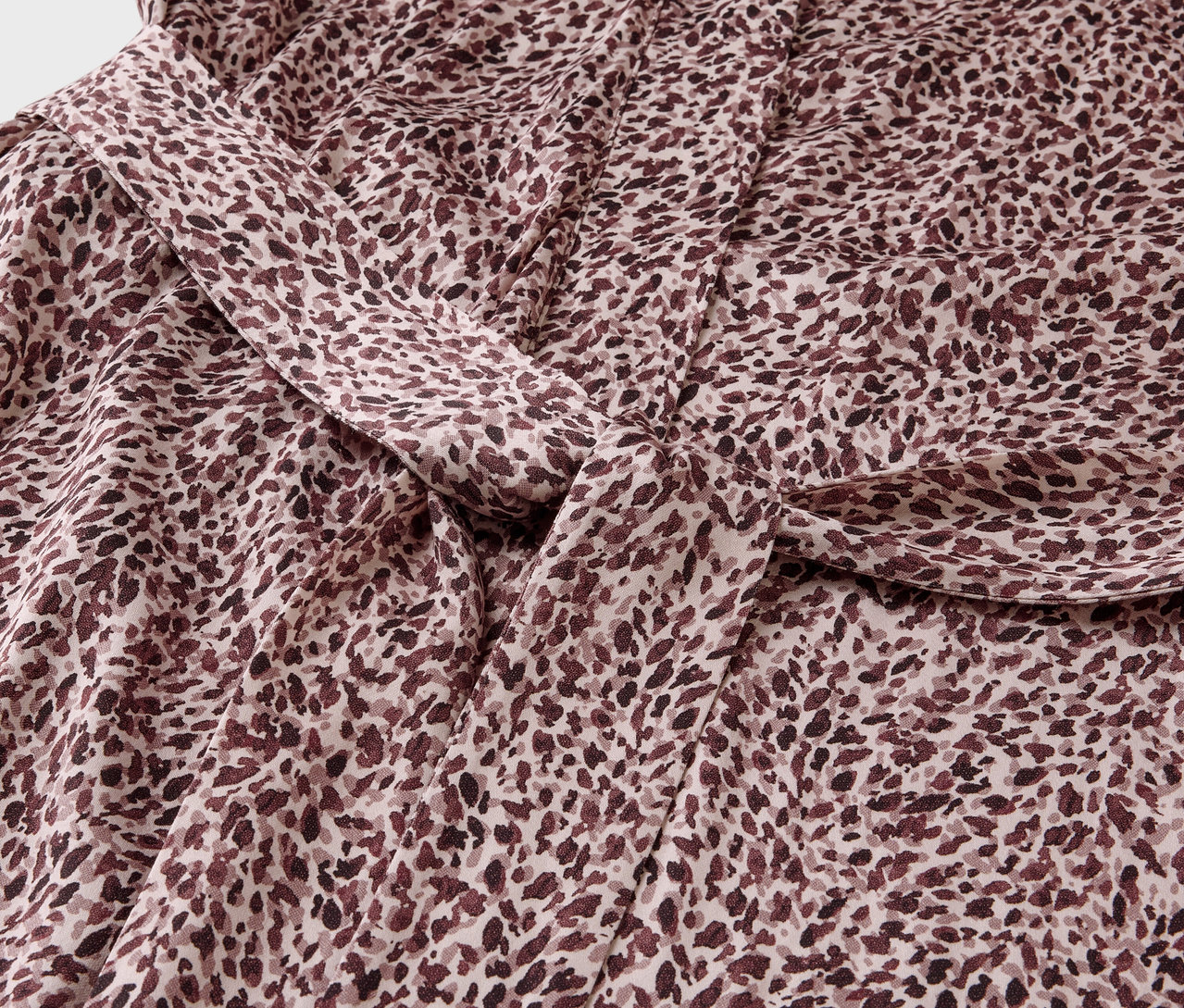 Detailný záber na látku s hnedým škvrnitým vzorom a uzlom.