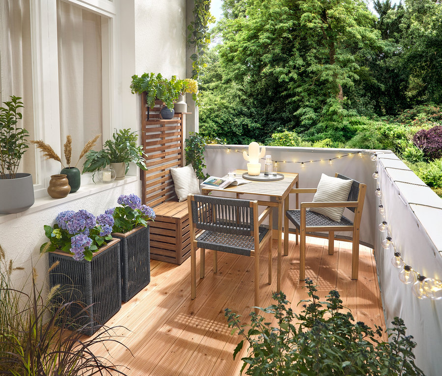 Zariadenie balkóna s balkónovou súpravou s textilnou výplňou, sivou balkónovou clonou a ochranou proti vetru, vonkajšou LED reťazou s adaptérom, kvetináčom s textilnou výplňou, vonkajšou LED akumulátorovou stolnou lampou, kaktusom a 2 vonkajšími vankúšmi s ľanovým povrchom.