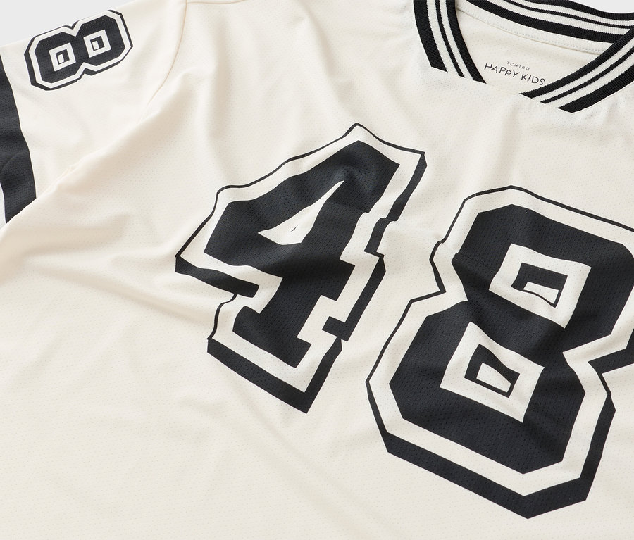 Detail trička s číslom 48 v čiernej farbe na krémovej látke.