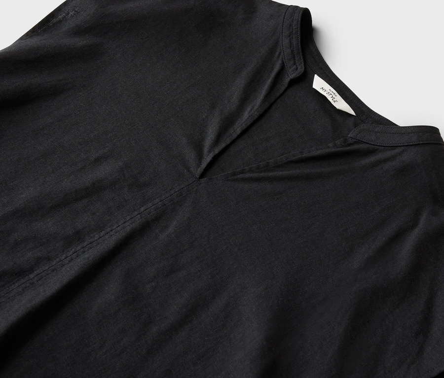 Detailný záber na čierny top s výstrihom do V a malým stojačikom na bielom pozadí.