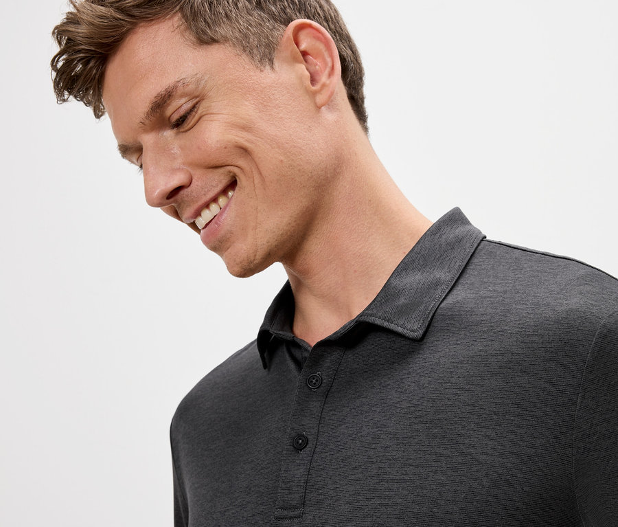 Usmievavý muž v šedom polo tričku.