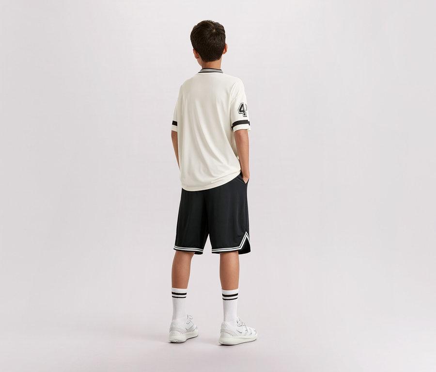 Mladík stojí chrbtom k fotoaparátu, má na sebe svetlé tričko s číslom 4, čierne šortky, biele ponožky a tenisky.