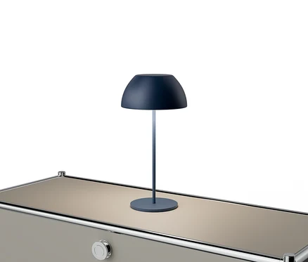 Modrá lampa stojí na béžovom stole so striebornými akcentmi.