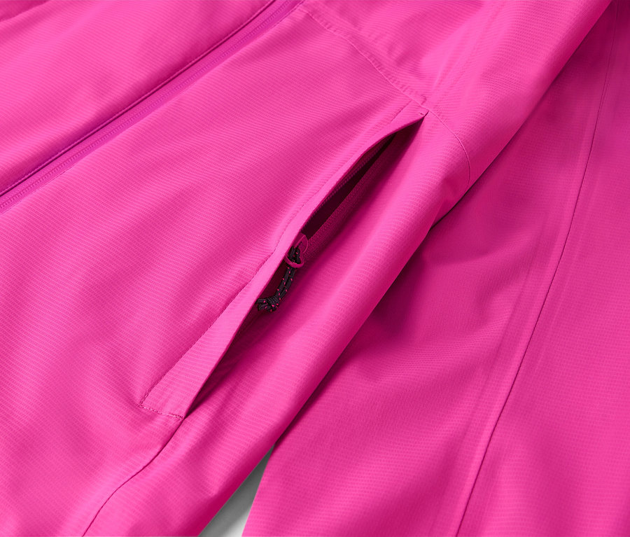 Detailný záber ružovej bundy s vreckom na zips.
