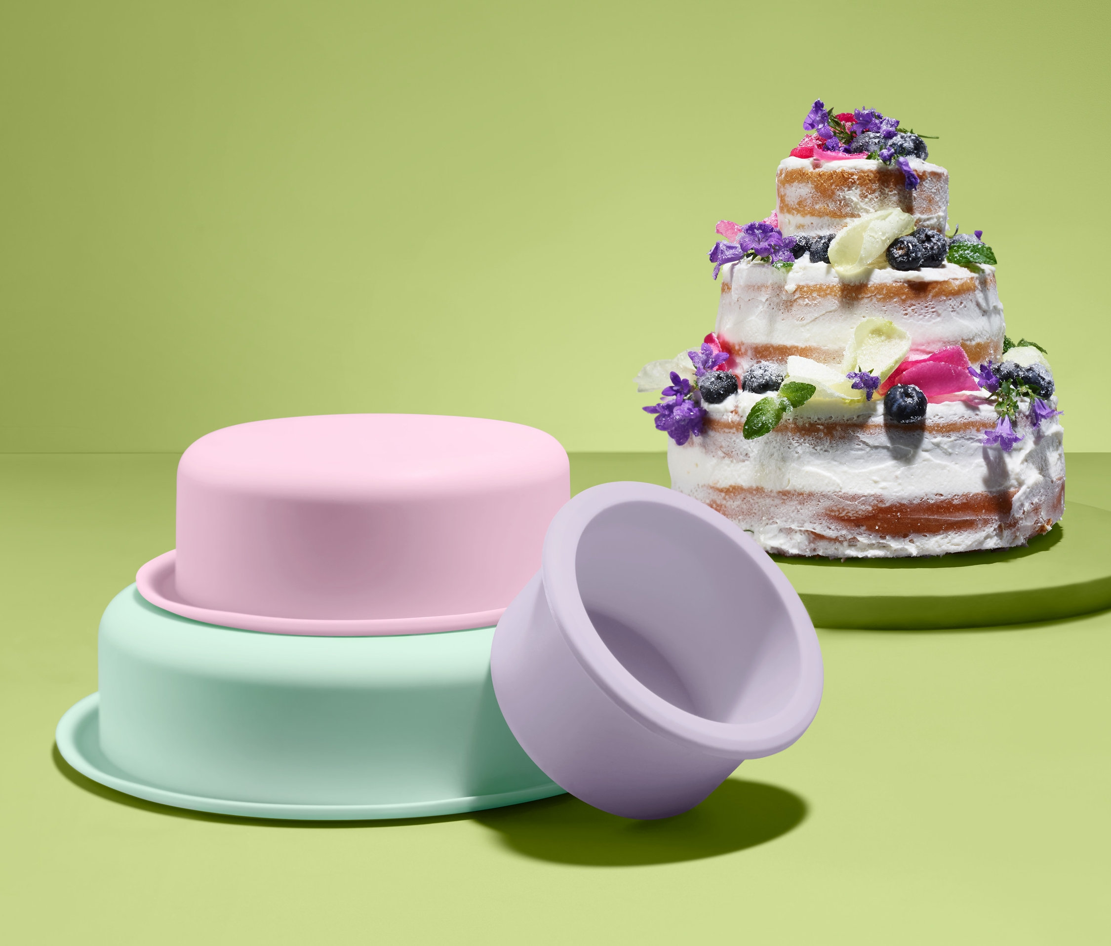 Viacposchodová torta zdobená kvetmi vedľa súpravy na pečenie tort.