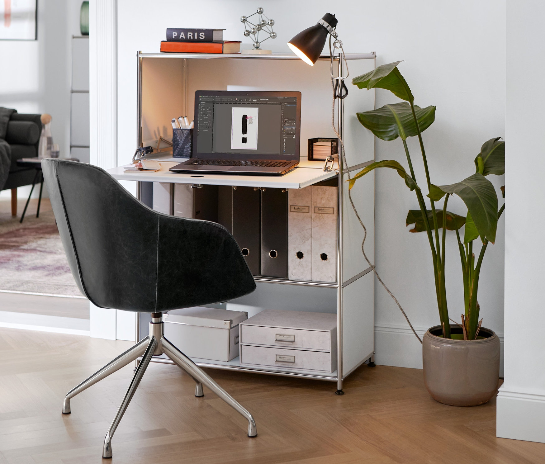 Čalúnená otočná stolička z koženky stojí pri bielej kovovej skrinke »CN3« s lampou so svorkou.