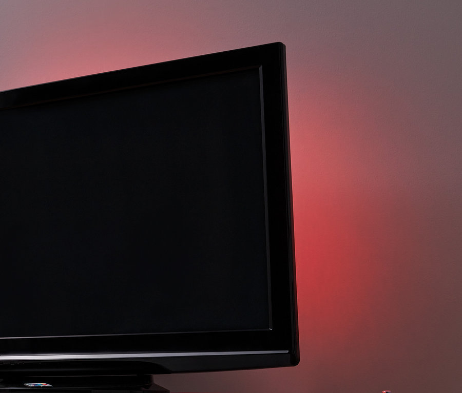 Čierny televízor s podsvietením TV s LED na bielom stolíku.