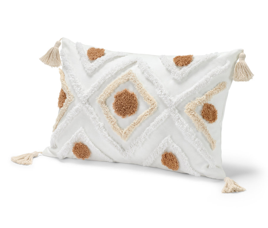 Biely dekoračný vankúš cca 40 x 60 cm s hnedými a bielymi vzormi a strapcami v rohoch.
