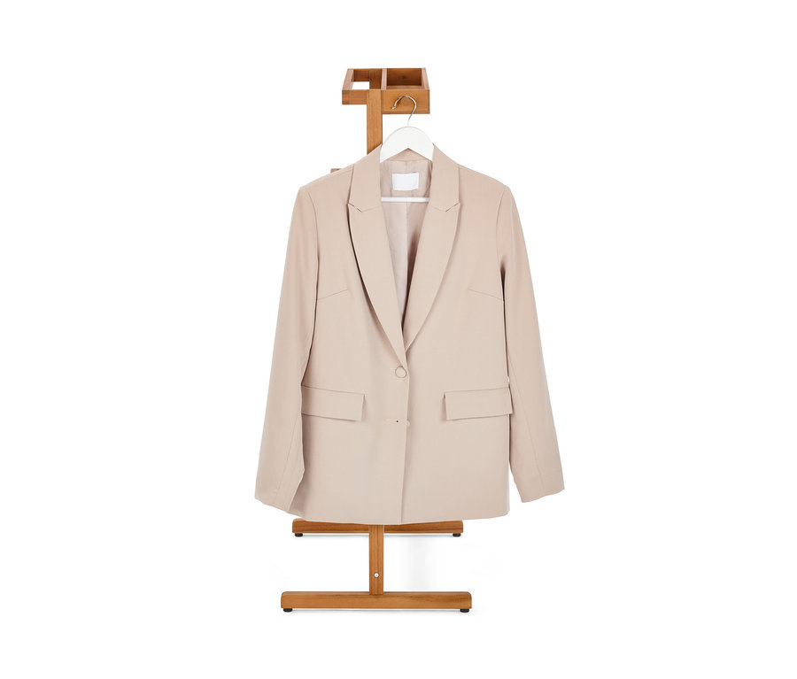 Béžové sako visí na nemom sluhovi.