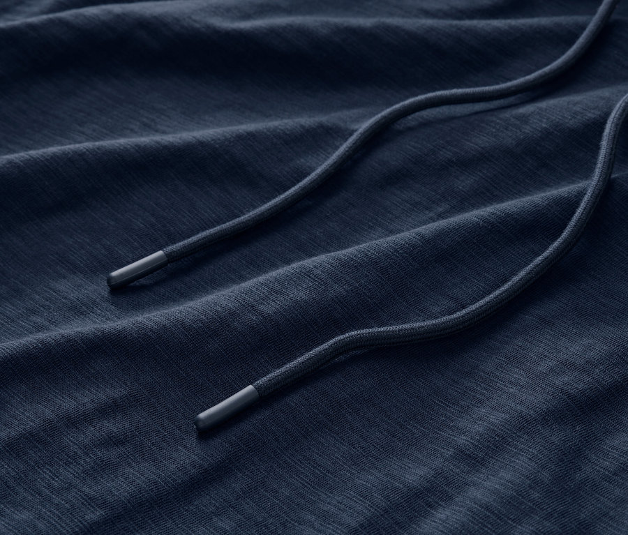 Detailný záber na látku námorníckej modrej džersejovej mikiny s kapucňou so sťahovacou šnúrkou.