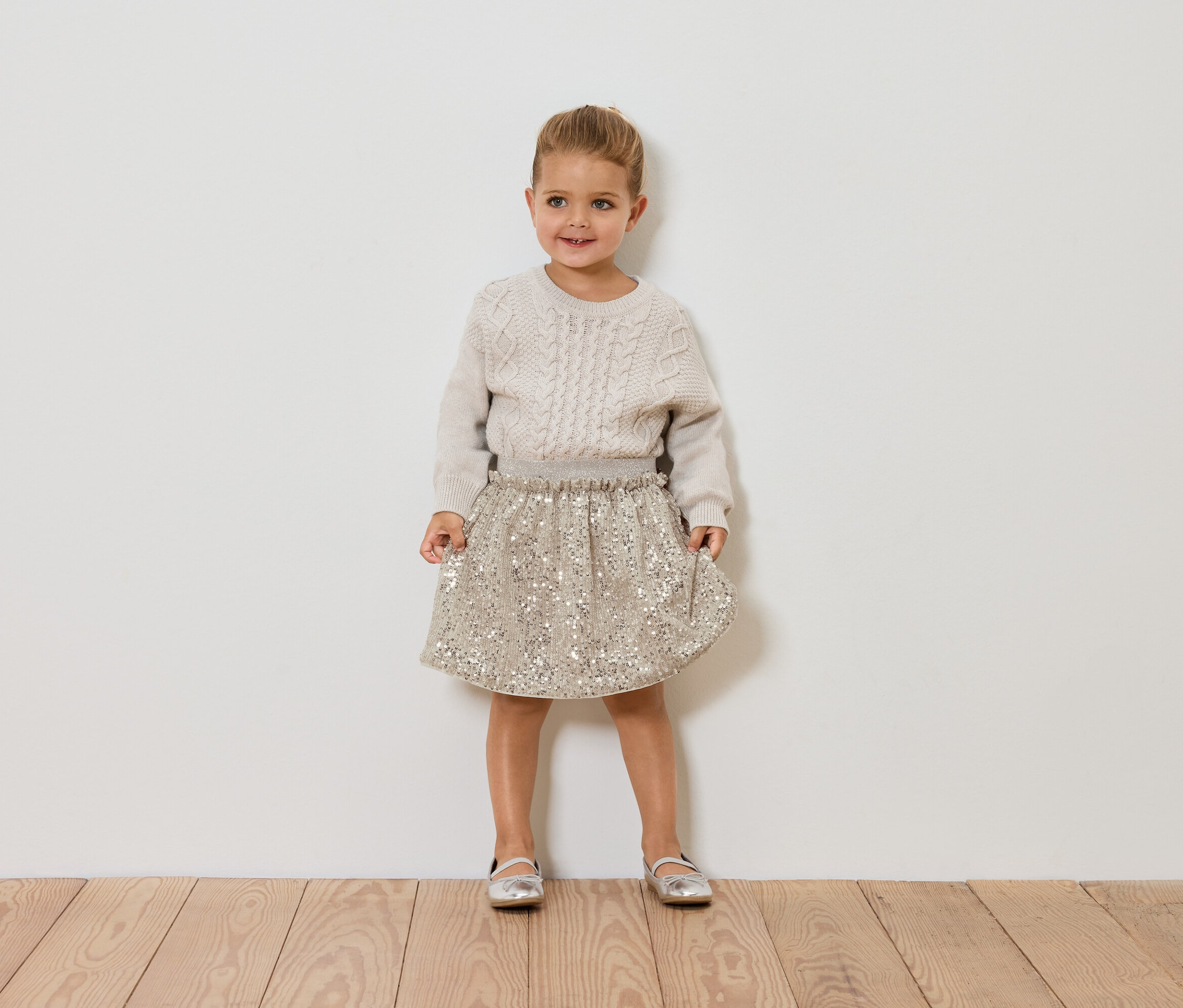 Dievča stojí a má na sebe sveter a sukňu.