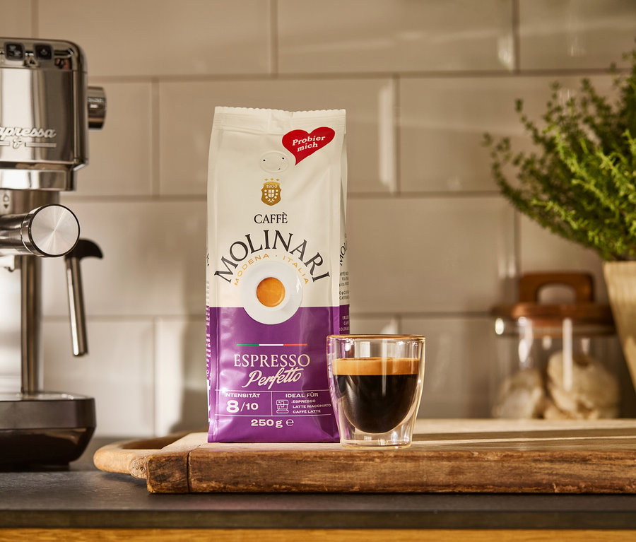 Strieborný kávovar »Lapressa«, balíček Caffè Molinari a šálka espressa na drevenej doske.