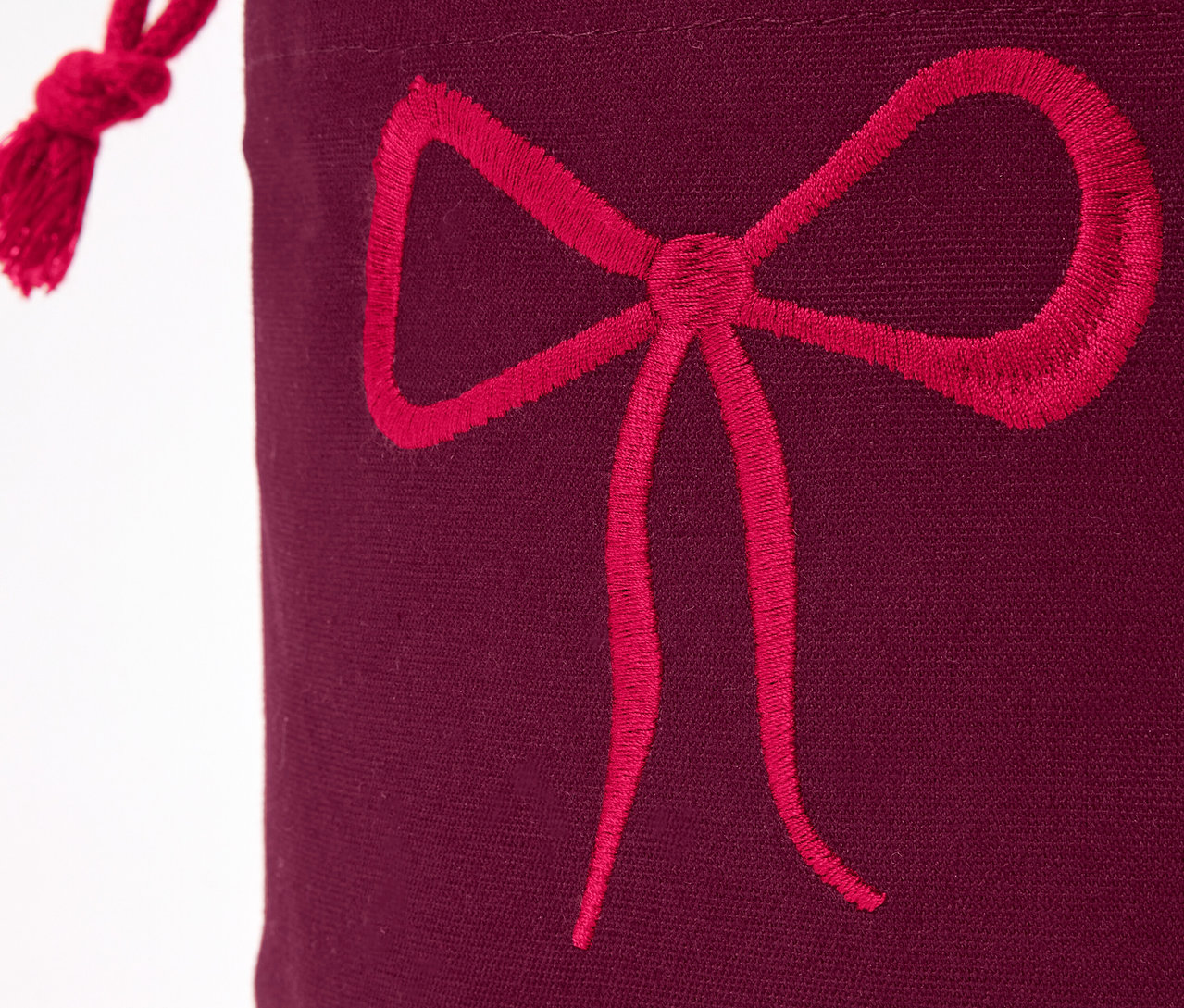 Detail bordovej darčekovej tašky s červenou mašľou.