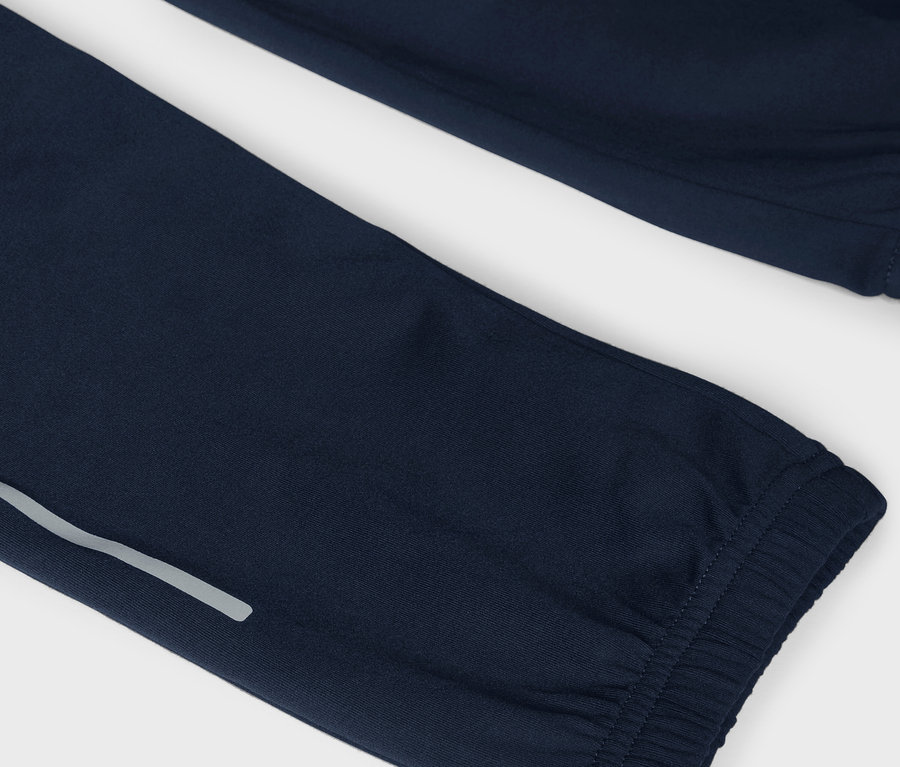 Detail tmavomodrých teplákov s reflexným pruhom.