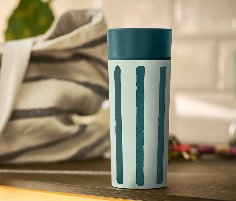 Pohár Coffee-to-go s prúžkami stojí na stole.