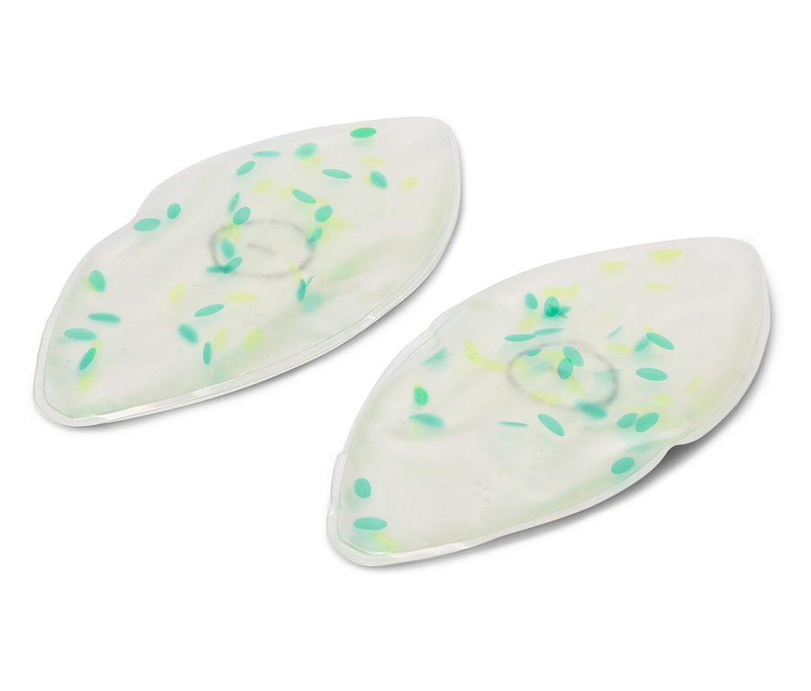 Dve biele gélové očné masky so zelenými a žltými bodkami ležia na bielom pozadí.