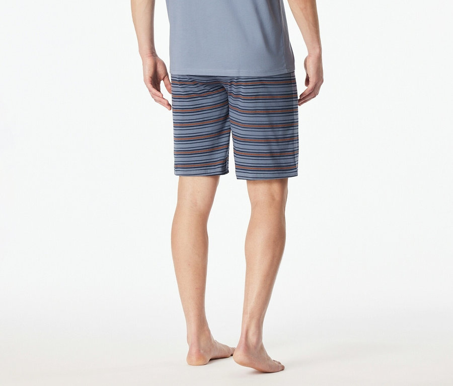 Pohľad zozadu na muža v modrom tričku a pruhovaných šortkách na bielom pozadí.