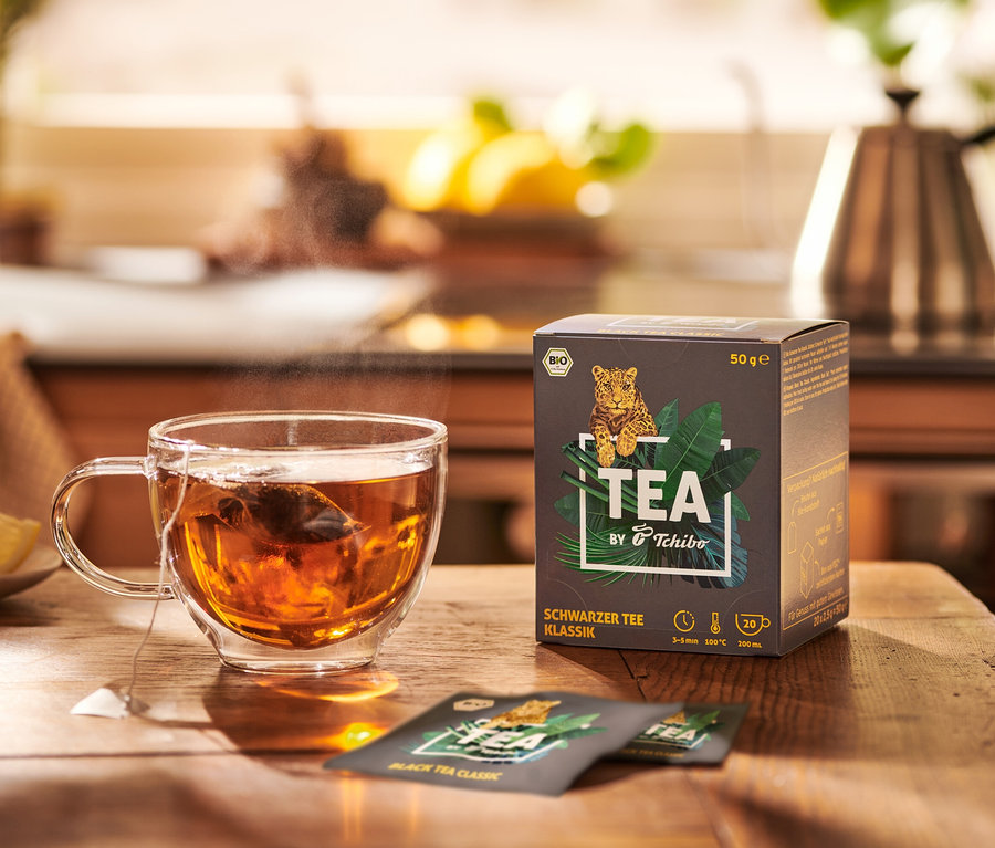 Šálka čaju vedľa balenia BIO TEA by Tchibo Klassik 8 x 20 x 2,5 g.