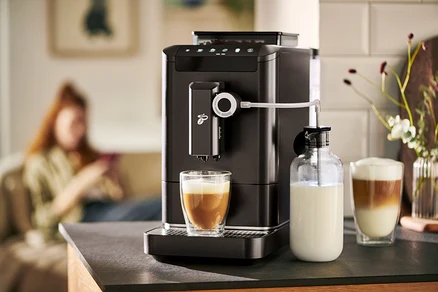 Automatický kávovar »Esperto 2 Milk« Granite Black pripravuje kávu do pohára. Vedľa stojí karafa na mlieko.