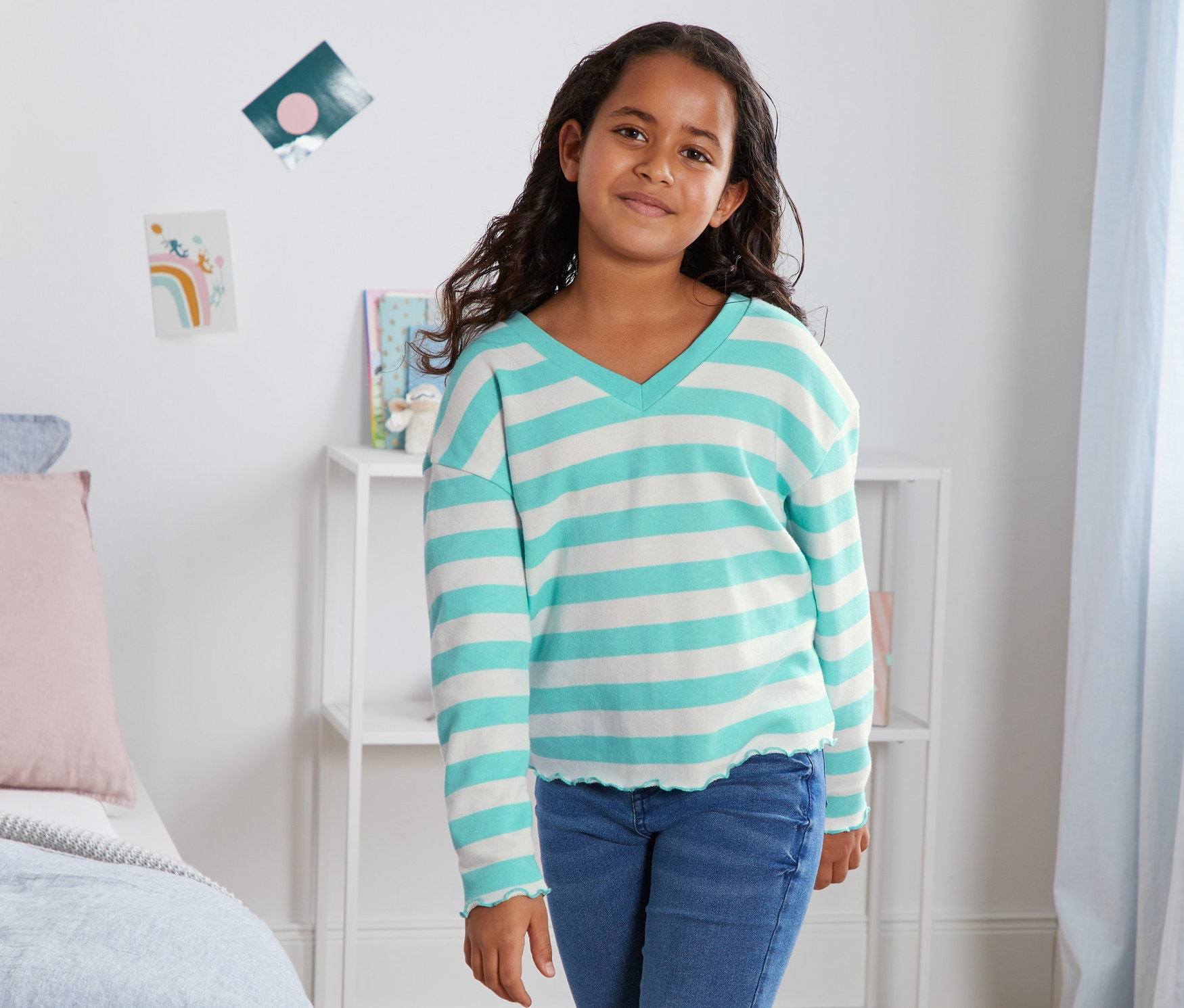 Dievča pózuje v bio bavlnenej mikine s modrými pruhmi.