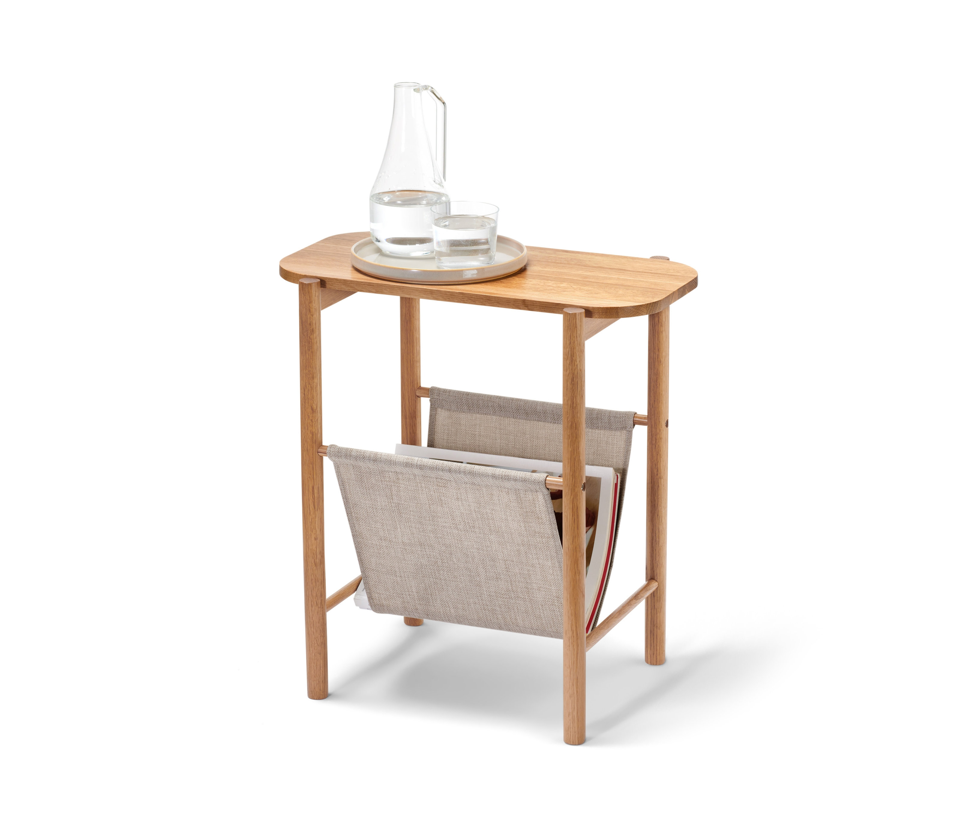Na odkladacom stolíku s látkovým úložným priestorom stojí karafa a pohár s vodou.