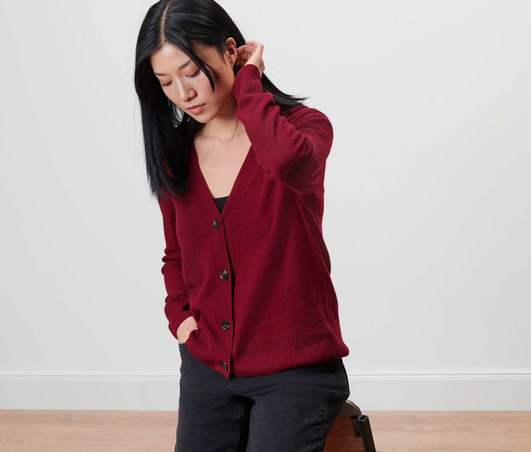 Žena sedí na stoličke a má na sebe sveter s kašmírom.