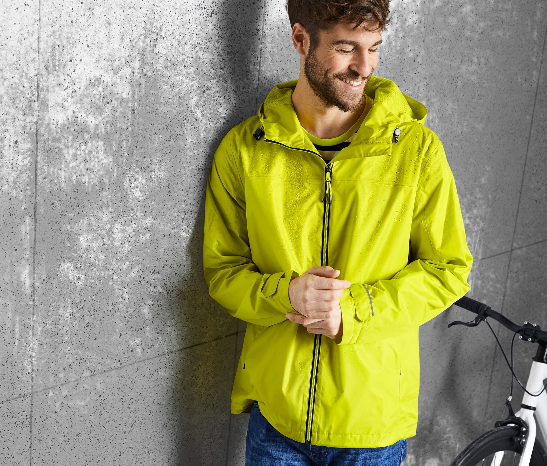 Muž opretý o stenu má na sebe žltú bundu do dažďa.