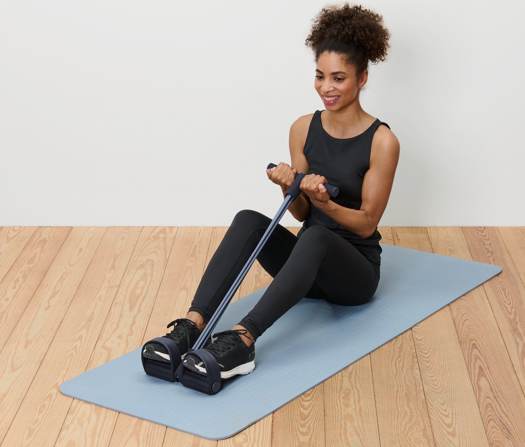 Žena sedí na podložke a používa posilňovač brucha a chrbta.