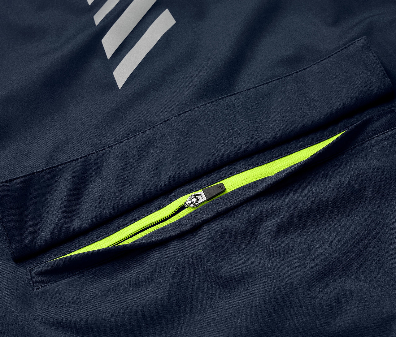 Detail modrej cyklistickej vetrovky Rad-Regenjacke s neónovo zeleným zipsom na vrecku a reflexnými prvkami.