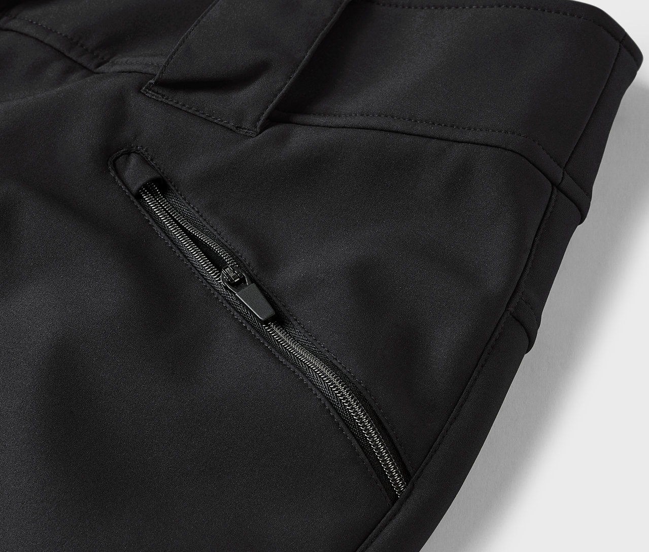 Detail čiernych nohavíc s vreckom na zips.