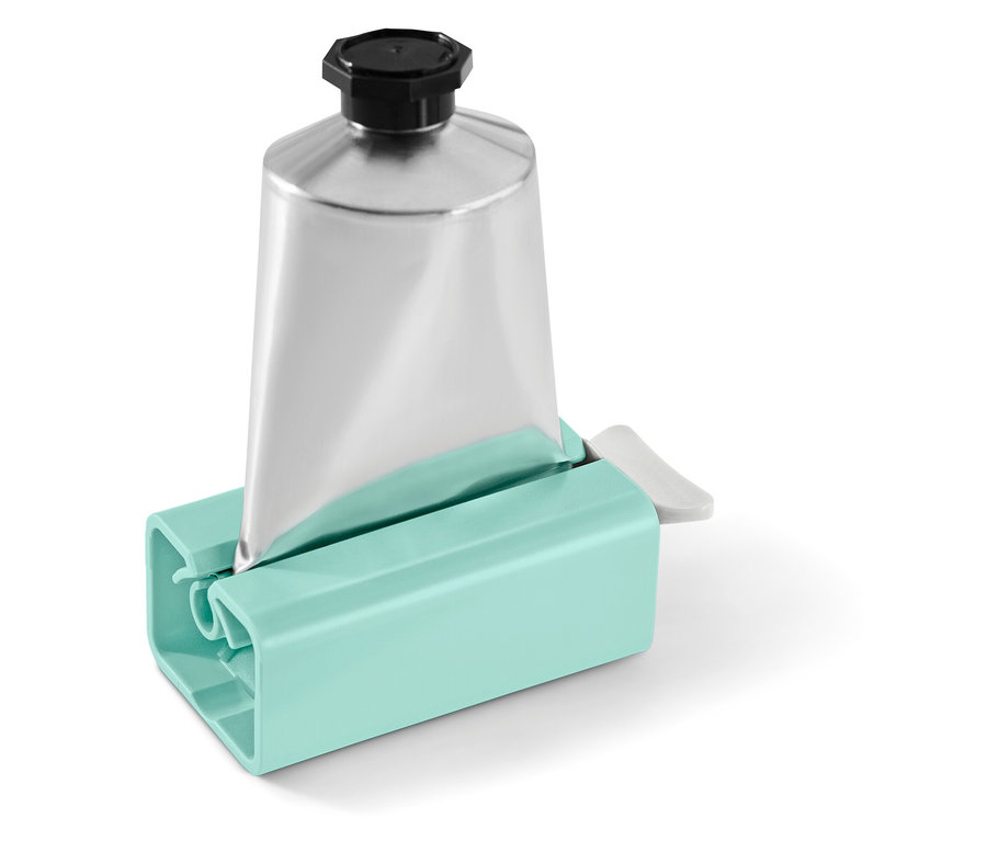 Strieborná tuba s čiernym uzáverom v tyrkysovom vytláčači na tuby.