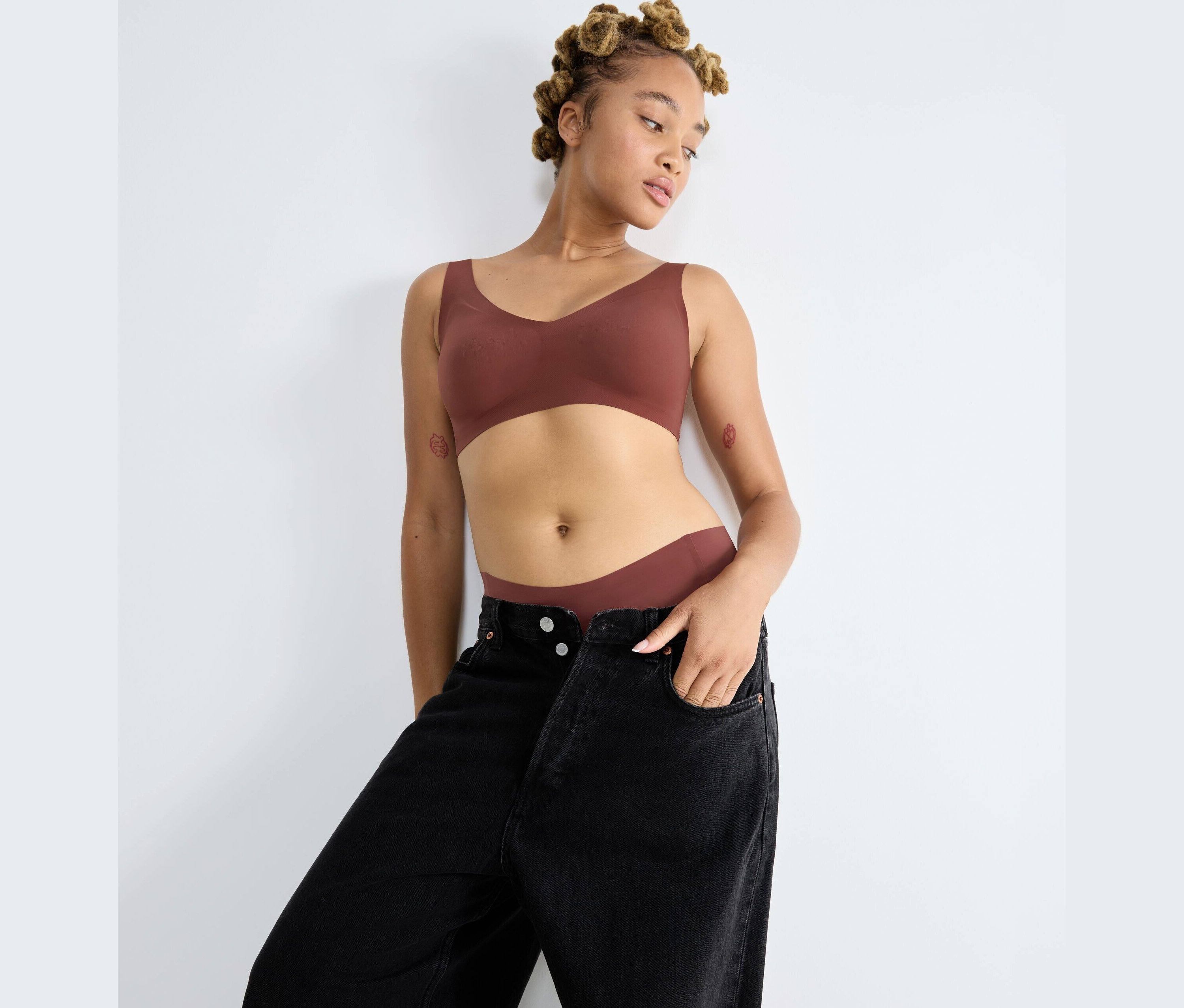 Žena pózuje v braletke sloggi ZERO Feel 2.0 a čiernych džínsoch.