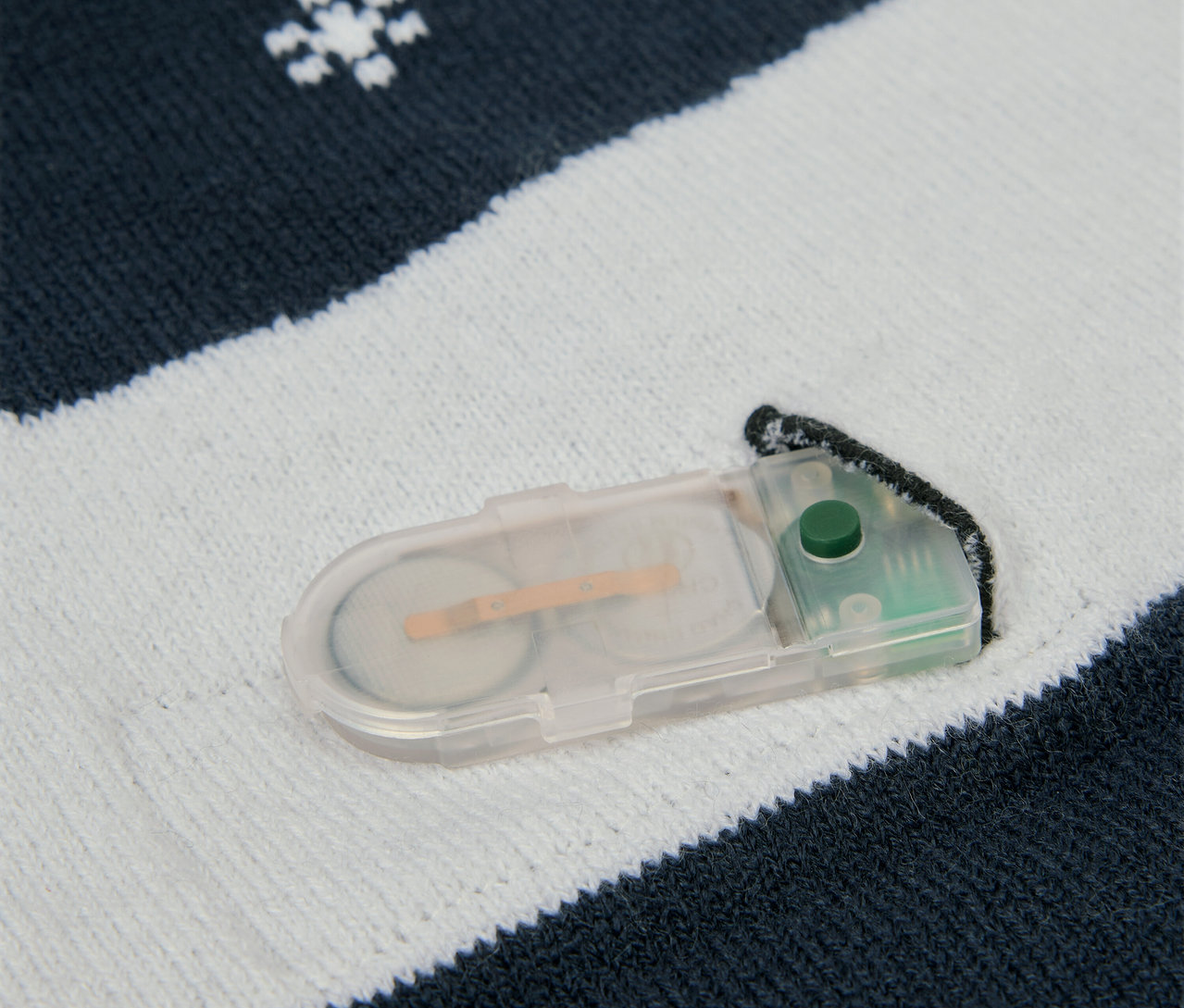 Detail pletenej látky so snehovými vločkami a puzdrom na batérie