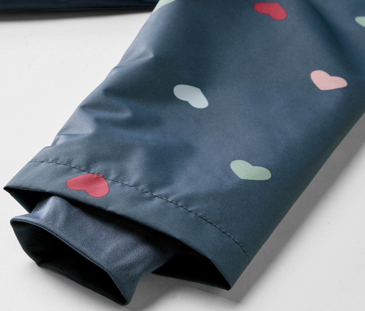 Detail detskej termo bundy do dažďa so vzorom srdiečok.