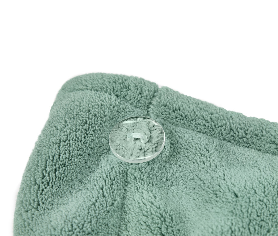 Detailný záber na tyrkysovo zelený turban na uterák s priehľadným gombíkom.